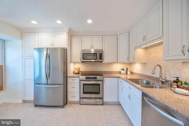 a kitchen with stainless steel appliances granite countertop a refrigerator a stove a sink and a microwave