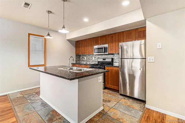 a kitchen with stainless steel appliances granite countertop a refrigerator a stove a sink and a refrigerator