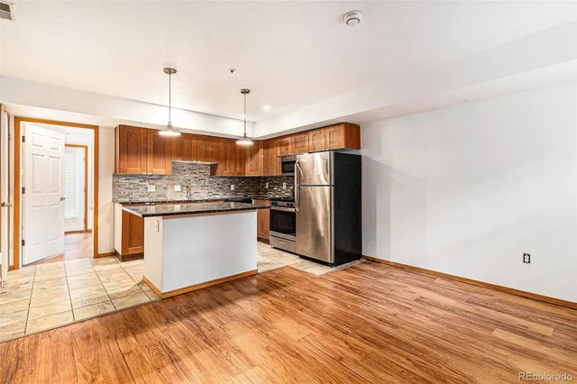 a kitchen with stainless steel appliances a refrigerator and wooden floor