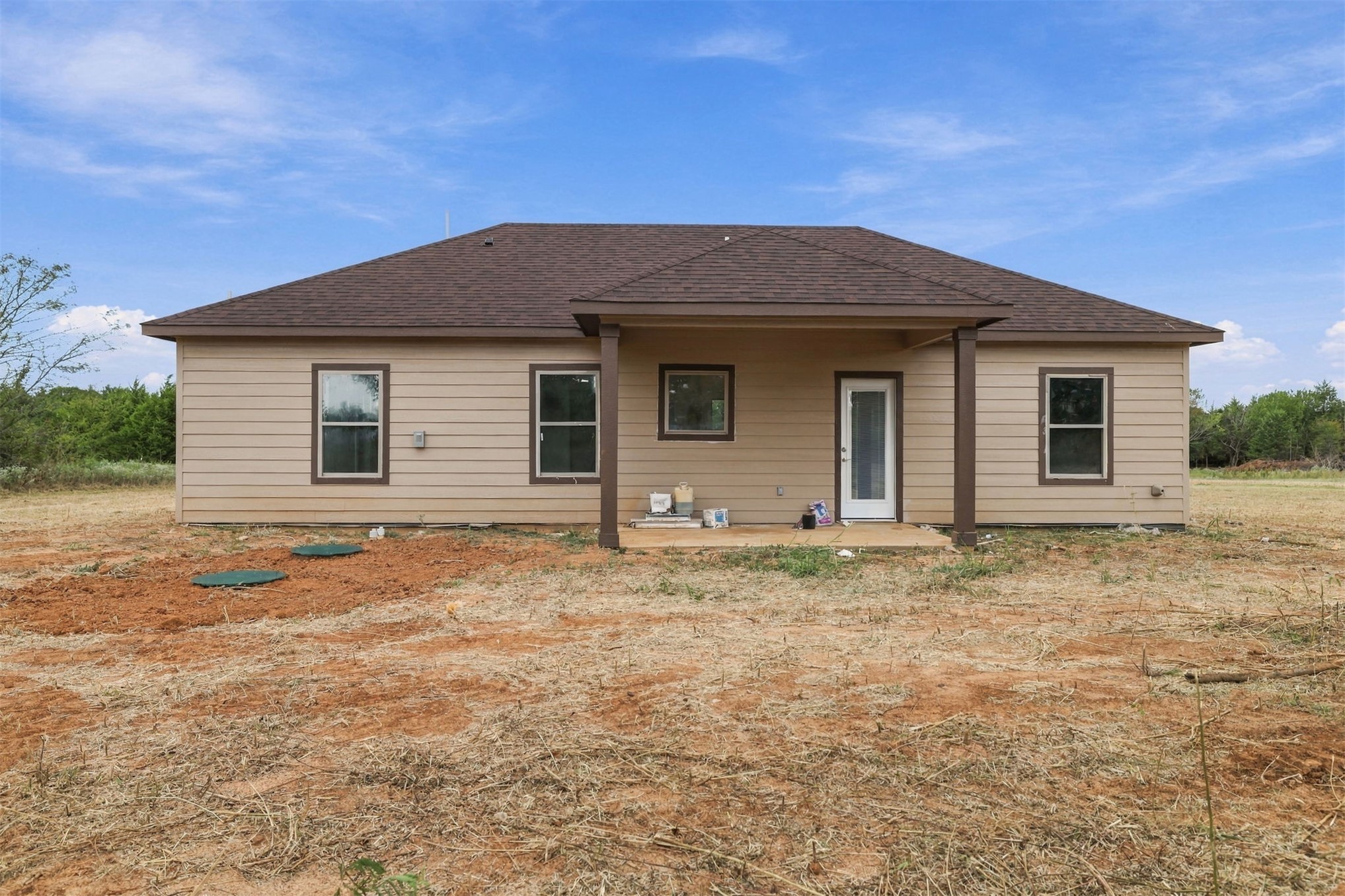 21 Redbird Lane Colbert, OK 74733 - Photo 22 of 27 Rear exterior with beige horizontal siding and brown trim