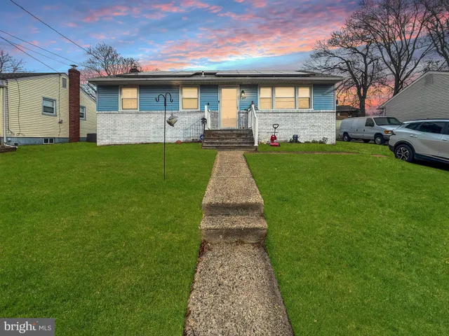 a front view of a house with a garden and trees