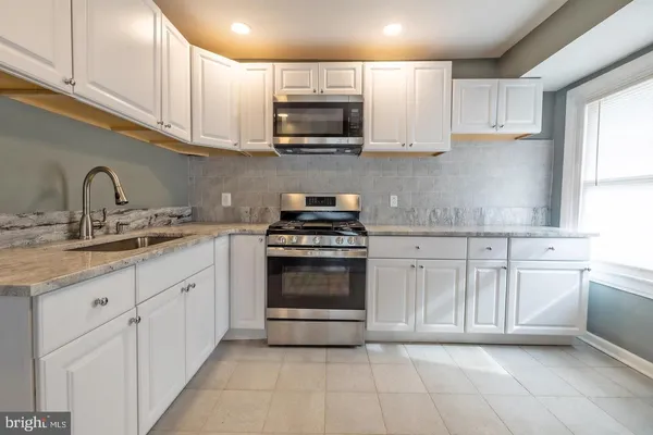a kitchen with granite countertop a stove top oven microwave and cabinets