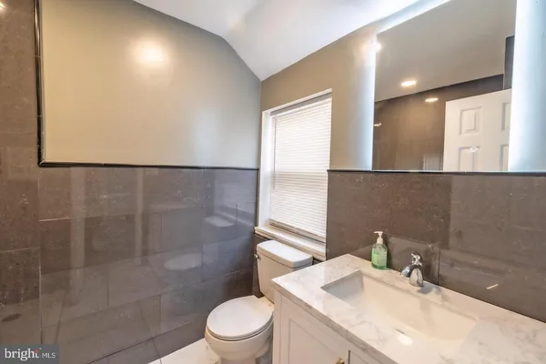 a bathroom with a granite countertop sink a toilet and shower