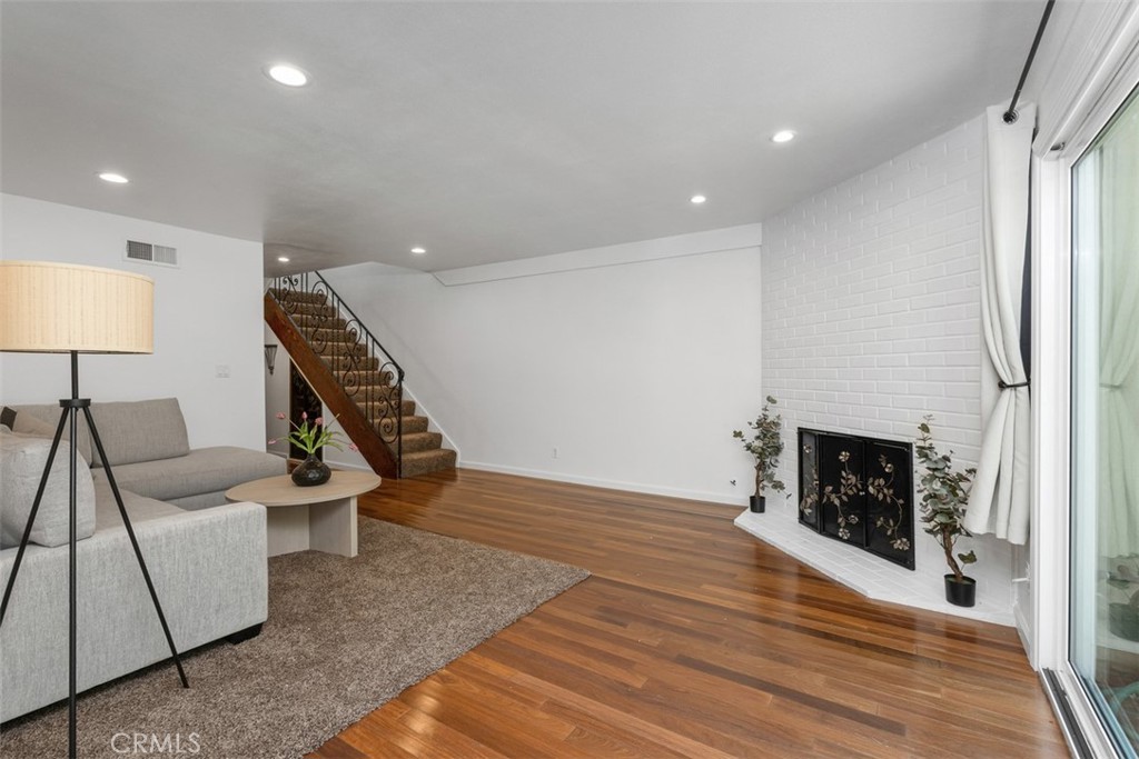 1741 Tustin Avenue, Unit 17C Costa Mesa, CA 92627 - Photo 5 of 36 a view of a livingroom with wooden floor and a fireplace