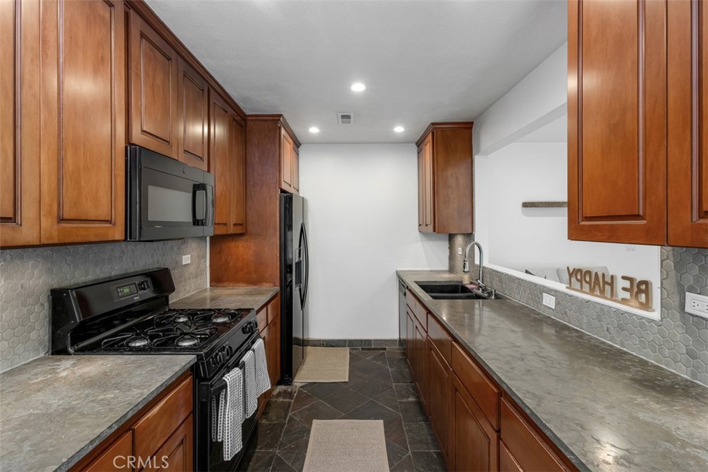 1741 Tustin Avenue, Unit 17C Costa Mesa, CA 92627 - Photo 10 of 36 a kitchen with granite countertop stainless steel appliances and wooden cabinets