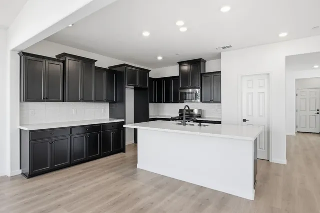 a kitchen with kitchen island stainless steel appliances a sink wooden floor and cabinets