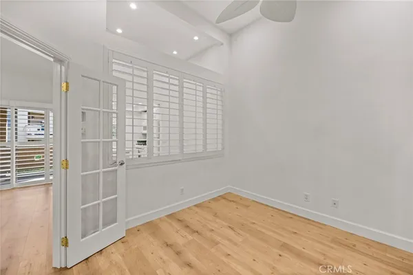 a view of empty room with wooden floor and fan