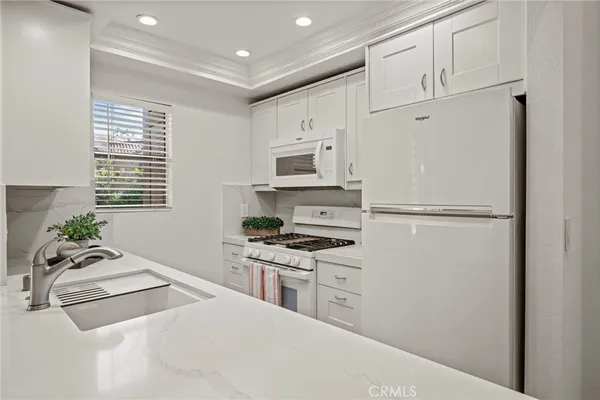 a kitchen with granite countertop a refrigerator stove top oven and sink
