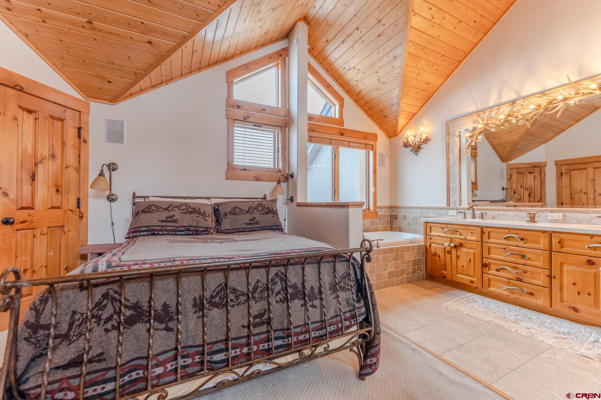 16 Snowmass Road, Unit 4 Crested Butte, CO 81225 - Photo 21 of 35 a bedroom with a bed a chandelier and dresser