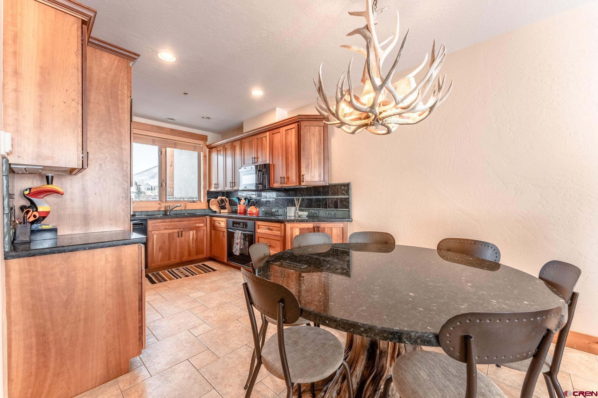16 Snowmass Road, Unit 4 Crested Butte, CO 81225 - Photo 9 of 35 a kitchen with stainless steel appliances granite countertop a stove a sink a dining table and chairs