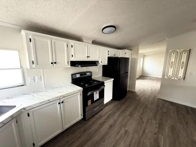 a kitchen with granite countertop a sink cabinets and stainless steel appliances