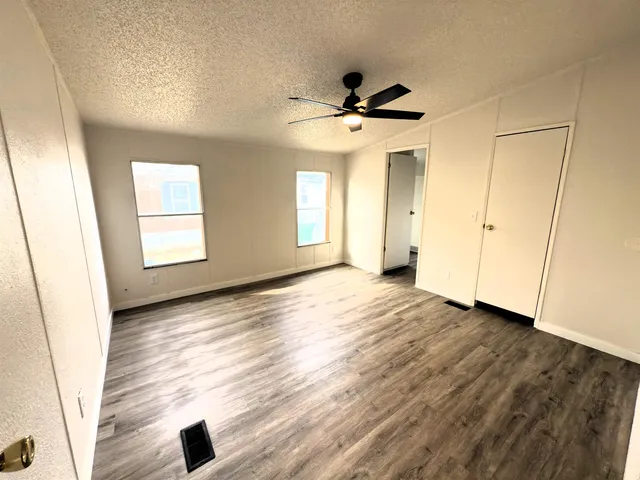 a view of an empty room with window and wooden floor