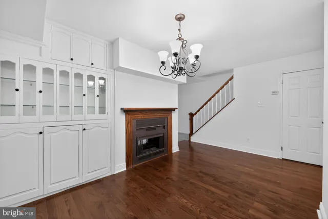a view of an empty room with wooden floor and a kitchen