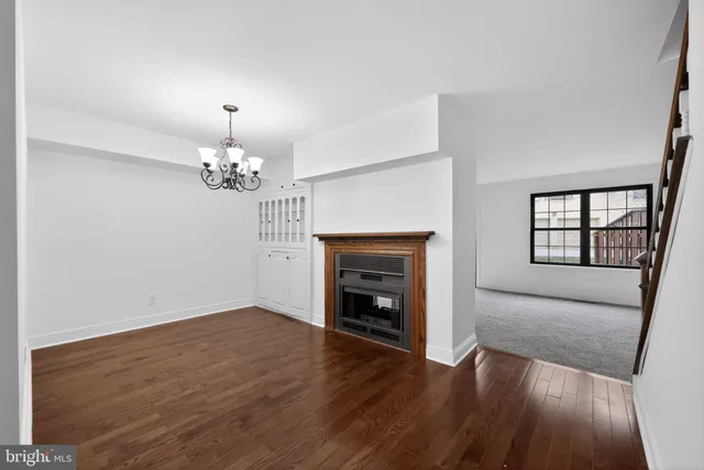 an empty room with wooden floor fireplace and windows