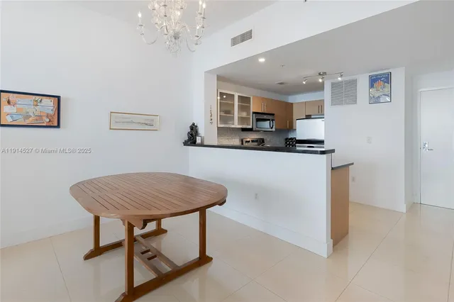 a kitchen with stainless steel appliances granite countertop a dining table chairs and a refrigerator