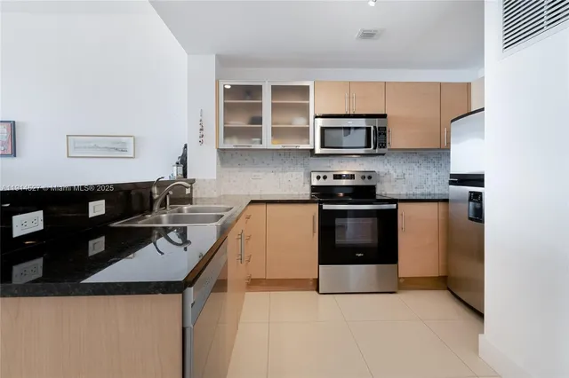 a kitchen with stainless steel appliances a stove a sink a microwave and a refrigerator