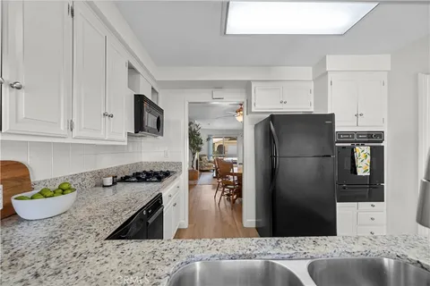 a kitchen with stainless steel appliances granite countertop a refrigerator a stove a sink a counter space and cabinets