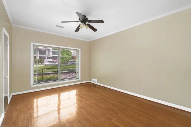 an empty room with wooden floor and a ceiling fan