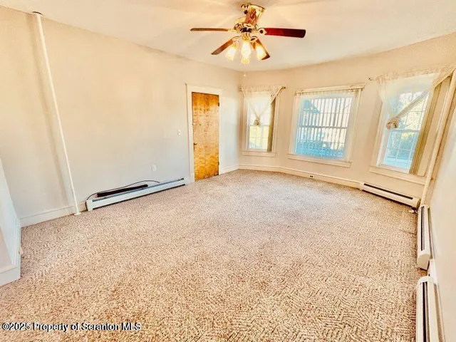 an empty room with windows and chandelier fan
