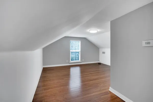 a view of an empty room with wooden floor and window