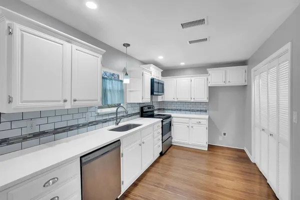 a kitchen with white cabinets appliances and sink