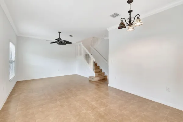 a view of an empty room with a chandelier fan