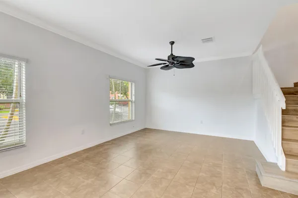 an empty room with windows and chandelier fan