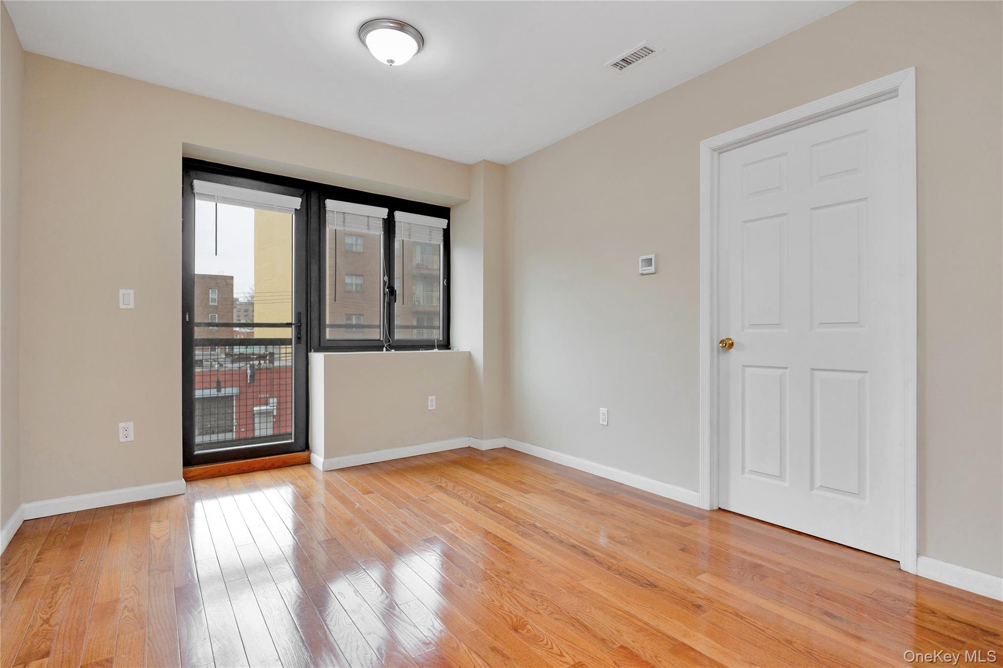 172-18 Jamaica Avenue, Unit 501 Queens, NY 11432 - Photo 12 of 27 a view of an empty room with wooden floor and a window