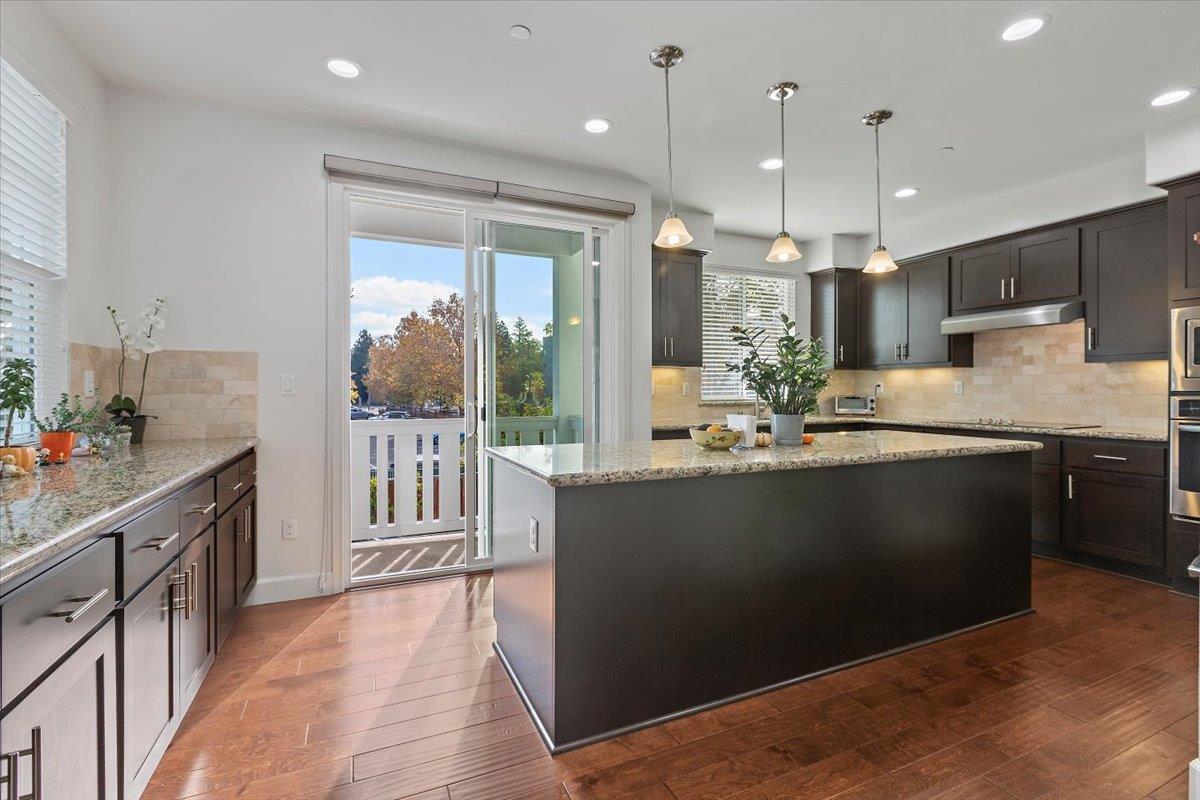 a kitchen with kitchen island granite countertop a large counter top covered in it and stainless steel appliances