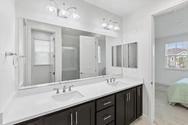 a bathroom with double vanity sinks a vanity a lamp and a mirror