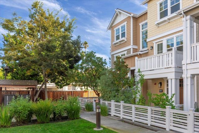 a view of a house with brick walls plants and large tree
