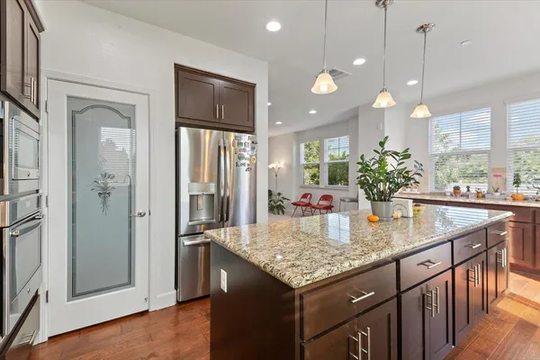 a kitchen with granite countertop kitchen island a refrigerator and a counter space