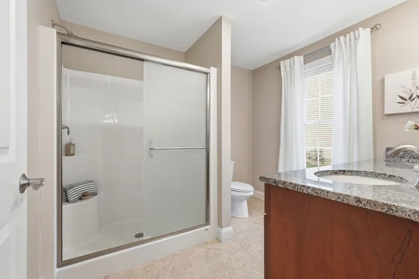 a bathroom with a granite countertop sink mirror and a toilet