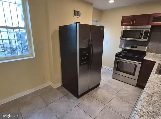 a kitchen with stainless steel appliances granite countertop a refrigerator and a stove top oven
