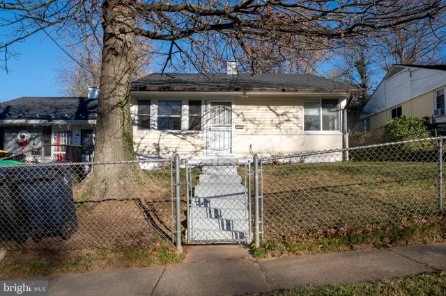 a view of a house with a large tree and wooden fence
