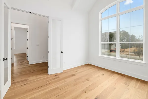 a view of an empty room with wooden floor and windows