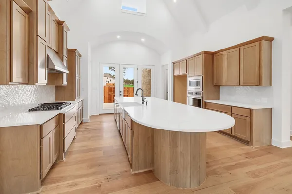 a large kitchen with stainless steel appliances kitchen island a large counter top and a stove top oven