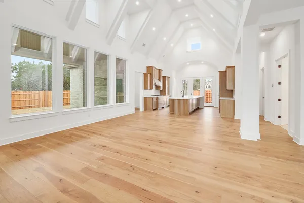 a view of an empty room with kitchen and a window