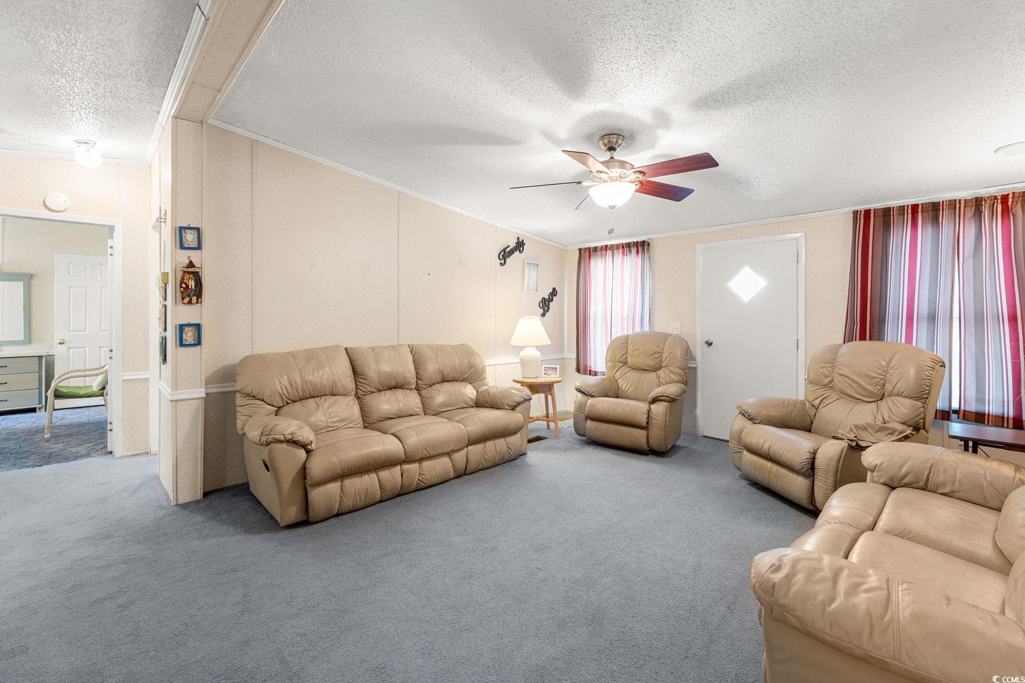 1509 Cove Lane Murrells Inlet, SC 29576 - Photo 18 of 38 Living room featuring a textured ceiling, carpet floors, crown molding, and ceiling fan