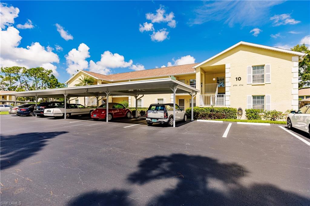 2750 Kings Lake Boulevard, Unit 204 Naples, FL 34112 - Photo 2 of 31 a view of building with parked cars