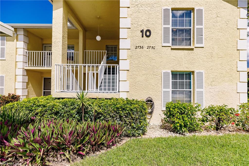 2750 Kings Lake Boulevard, Unit 204 Naples, FL 34112 - Photo 4 of 31 front view of a brick house with a yard