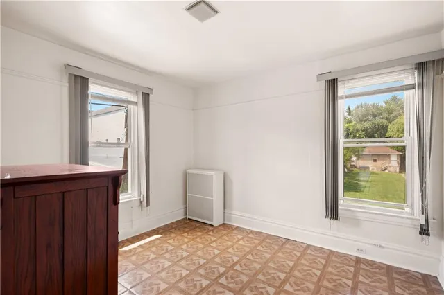 a view of an empty room with window and wooden floor