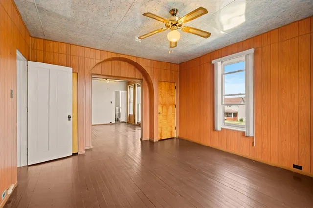 an empty room with wooden floor cabinet and windows