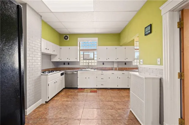 a large white kitchen with a lot of counter space and wooden floor