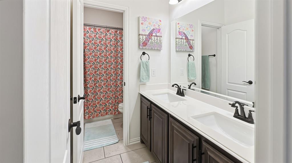 5216 Troupe Road McKinney, TX 75071 - Photo 34 of 40 Bathroom featuring a dual vanity with dark wood-finish cabinetry, white countertop, and integrated sinks with matte black fixtures