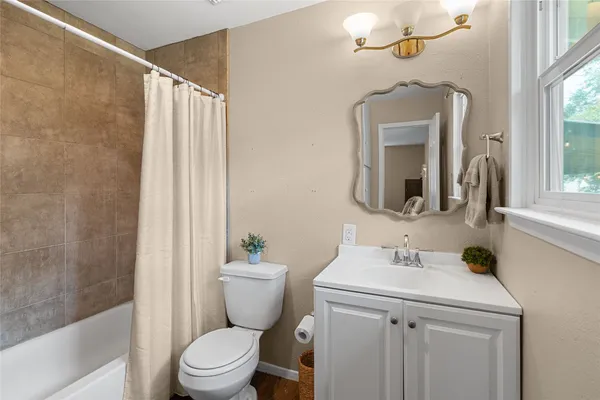 a bathroom with a sink a toilet a mirror and shower curtain