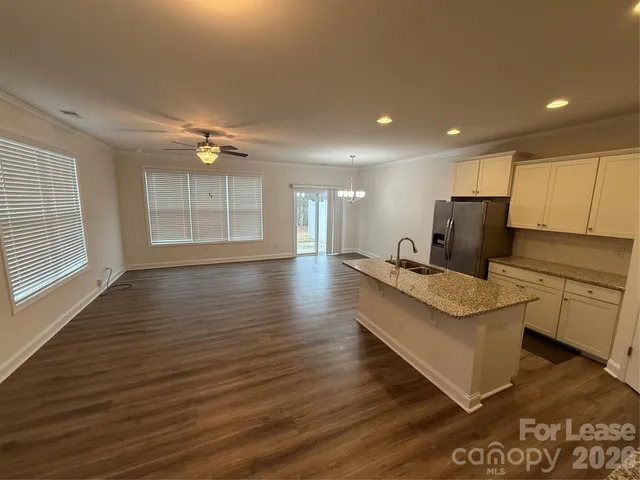 a large white kitchen with wooden floor and a window