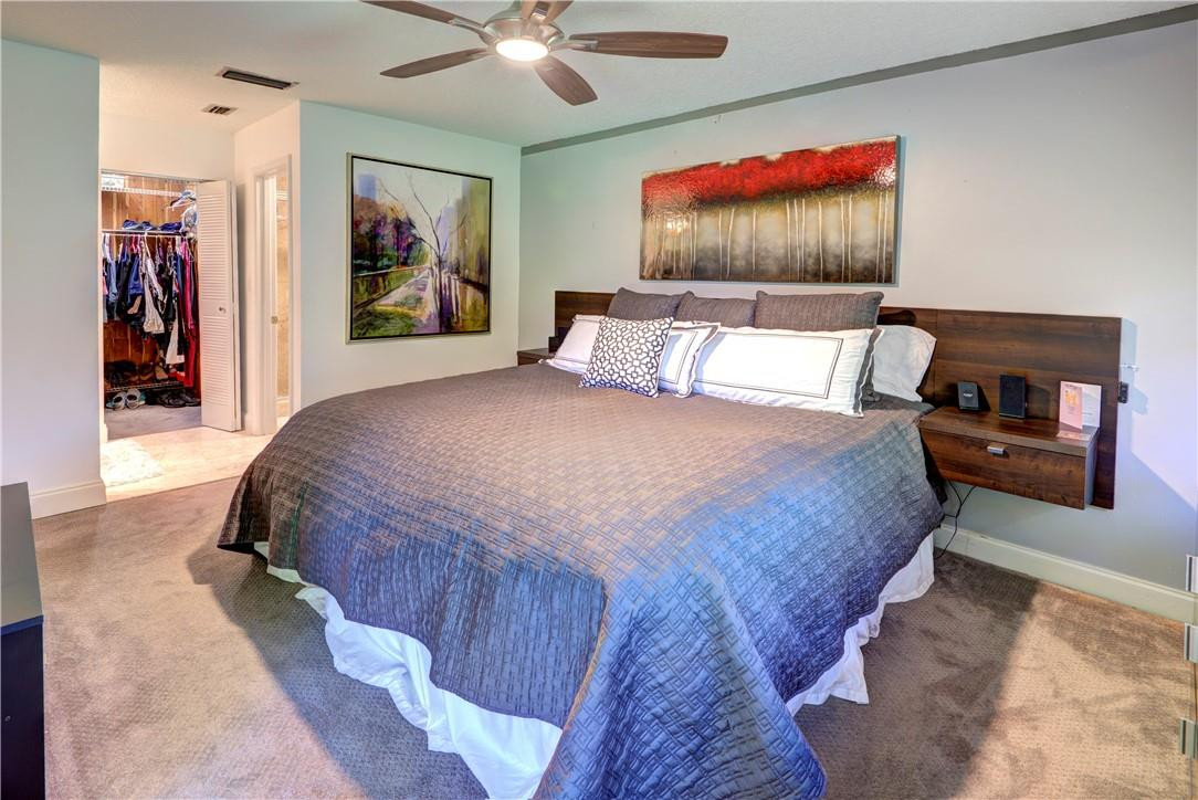 3130 Millwood Terrace, Unit M210 Boca Raton, FL 33431 - Photo 15 of 23 a bedroom with a bed and a chandelier