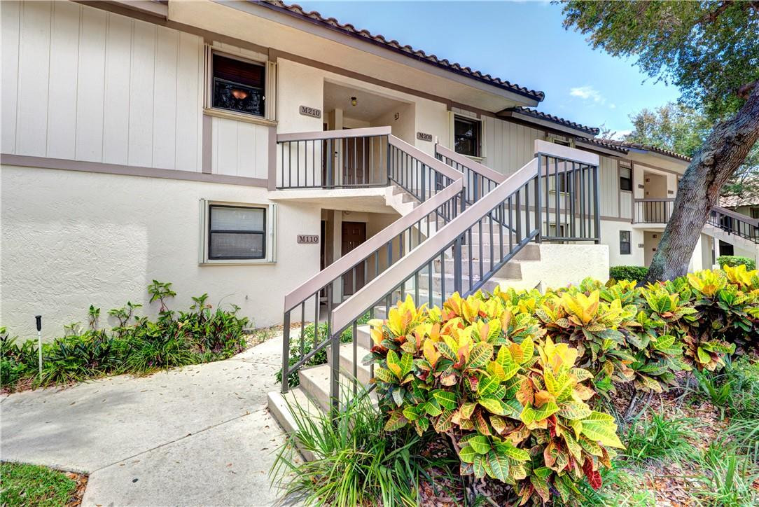 3130 Millwood Terrace, Unit M210 Boca Raton, FL 33431 - Photo 22 of 23 a front view of a house with a yard and fountain in middle