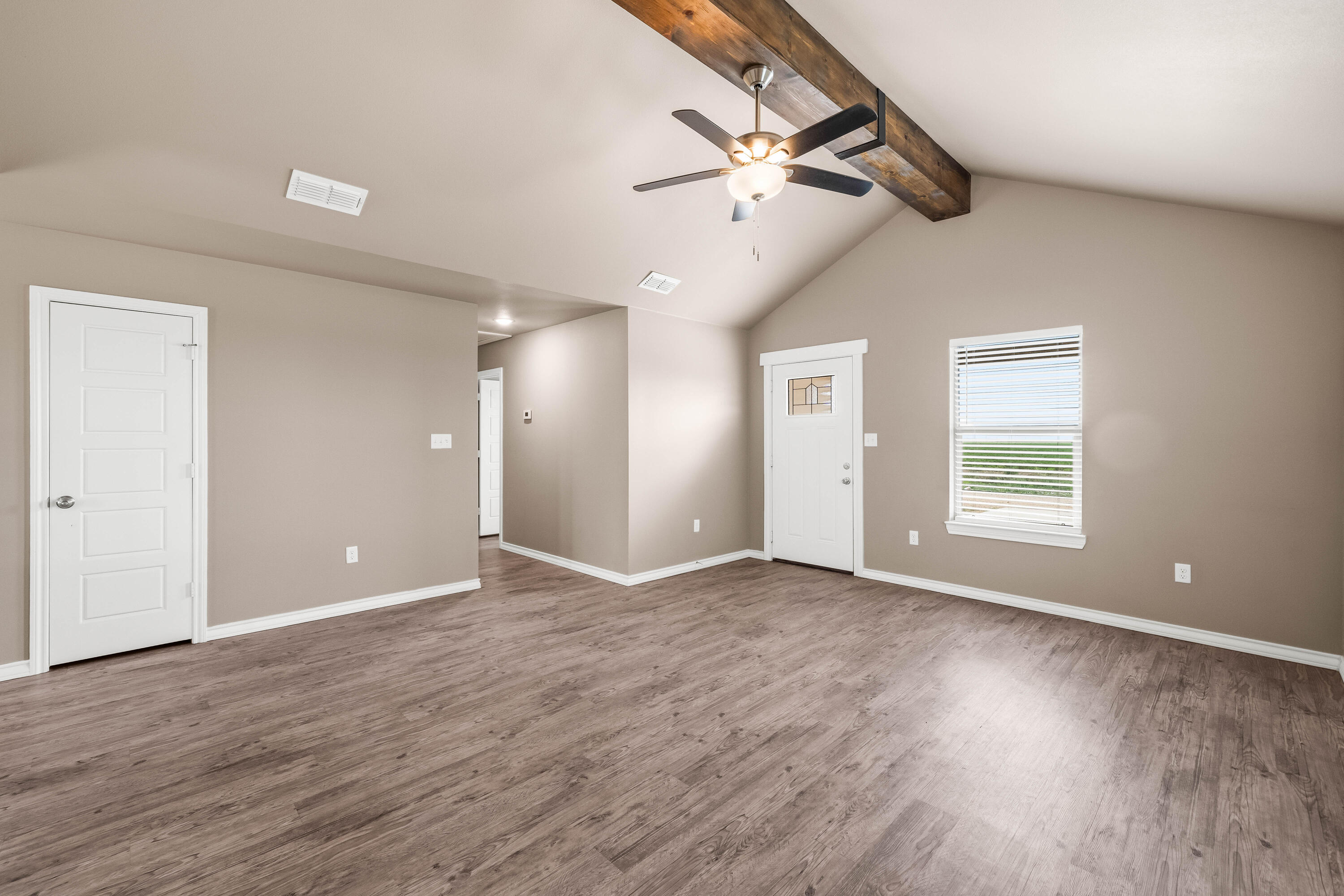 a view of an empty room with wooden floor and a window